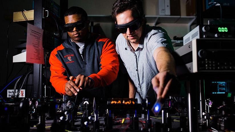 A student and professor work in the physics laser lab