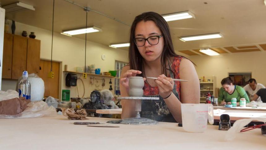 一名美高美网络平台游戏的学生在艺术工作室里用粘土工作