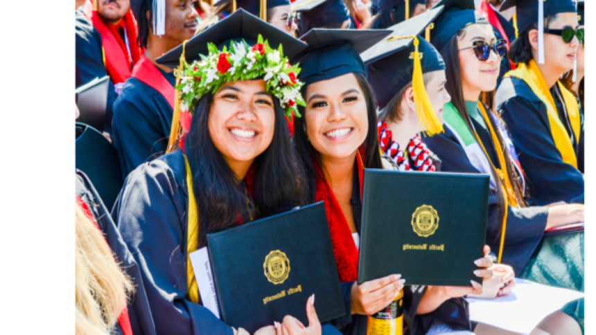 Two smiling Pacific students proudly hold up their Pacific University degrees.