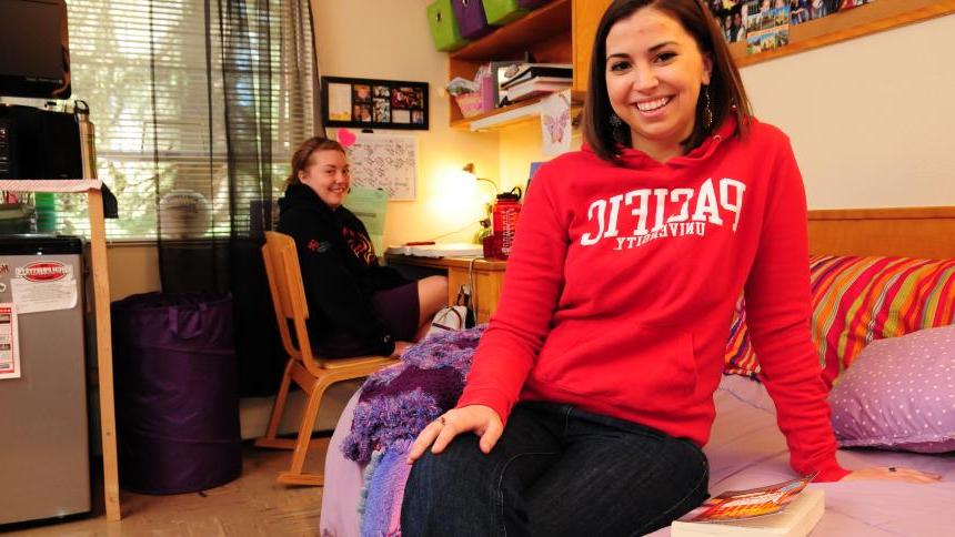 Two female Pacific students sit in their shared dorm room.