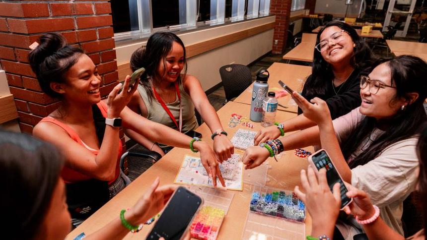 A group of students display friendship bracelets they have made during new student orientation.